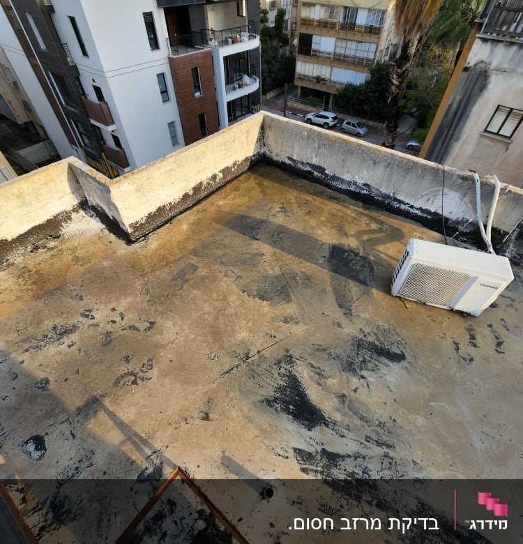 גג בטון עם כתמים שחורים ומזגן מותקן